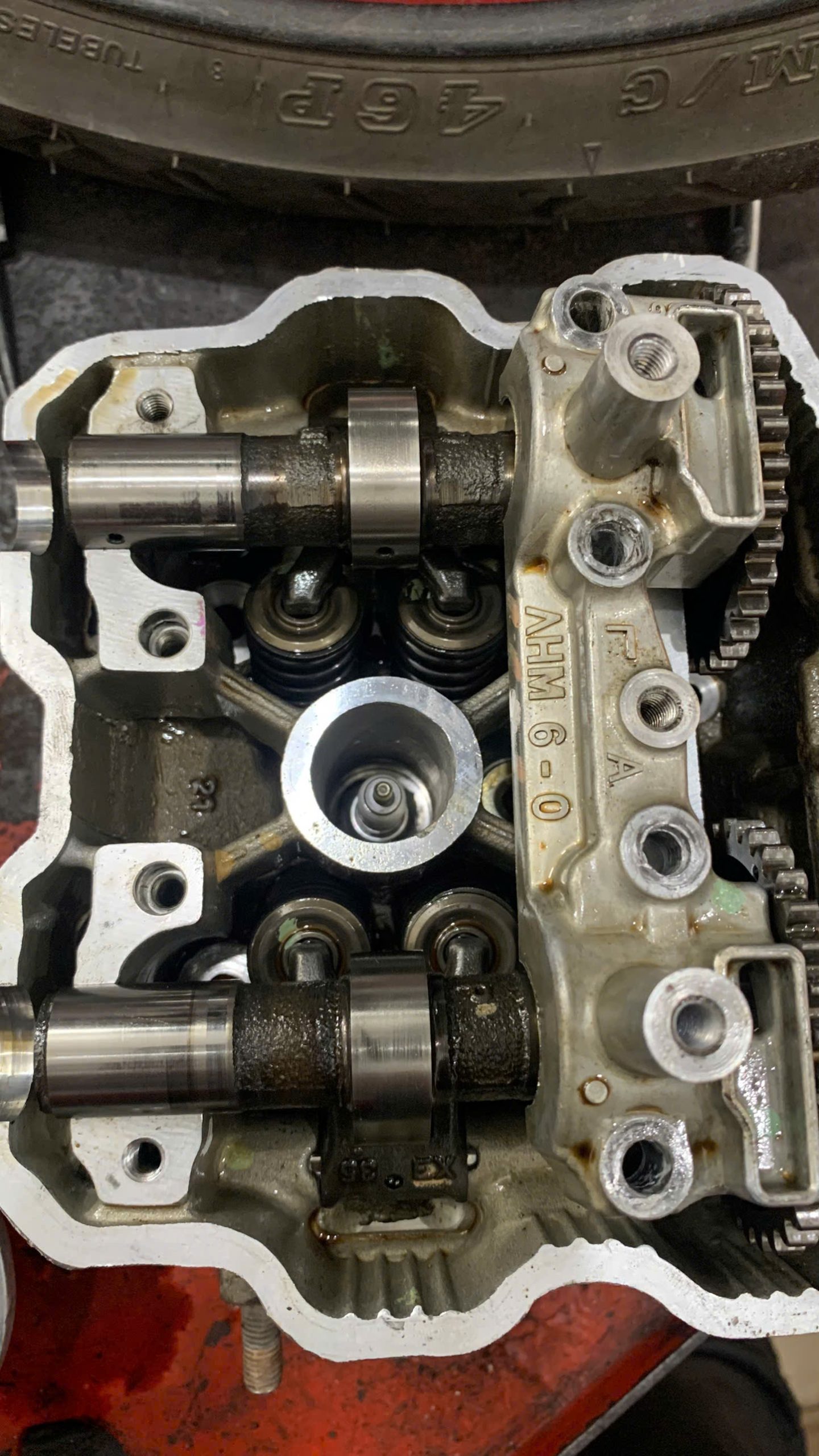 A close-up of a Honda Winner cylinder head with camshafts and valve springs exposed for repair in Ho Chi Minh City.