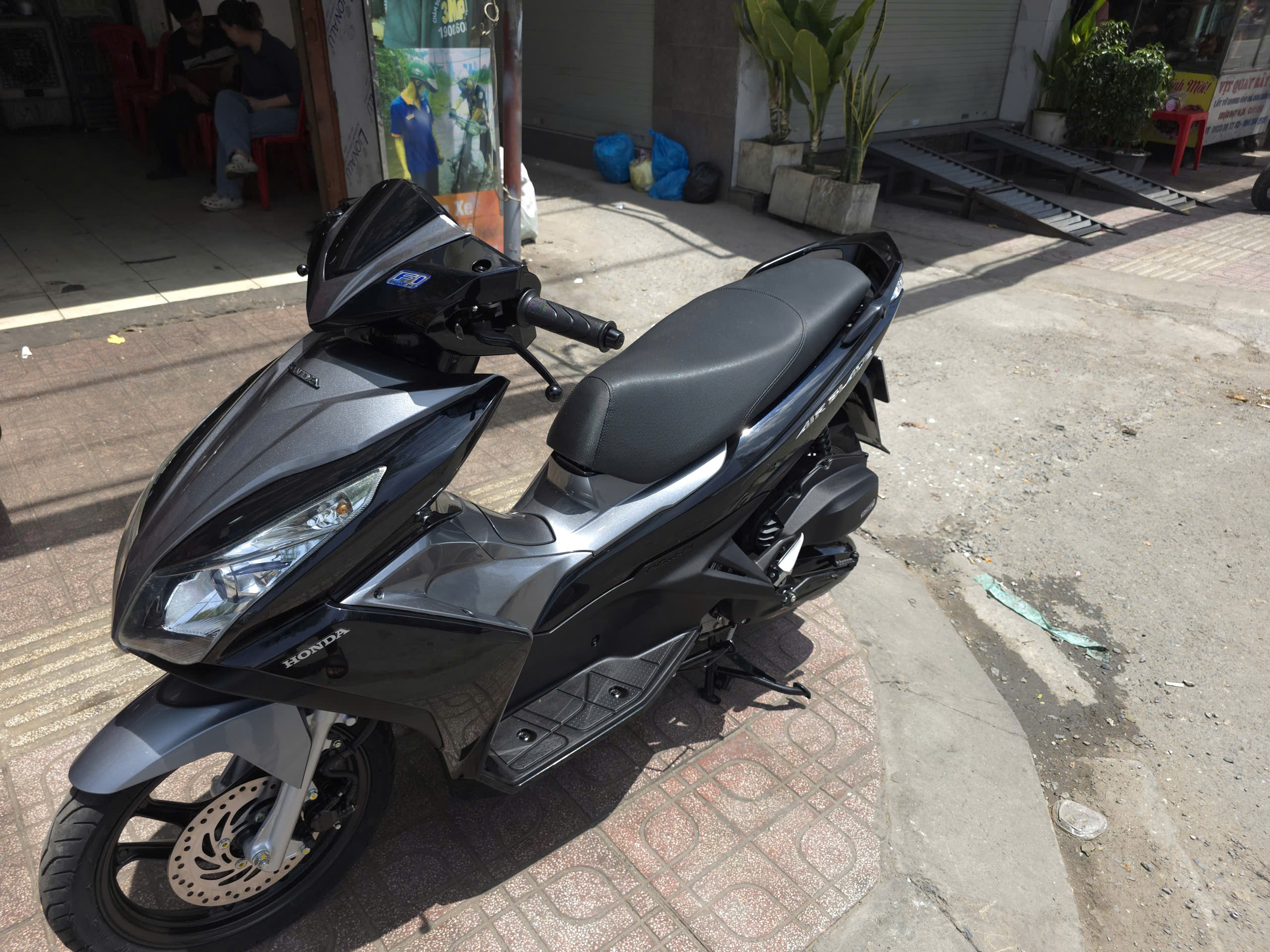 Side view of a gleaming black and silver Honda Air Blade after a complete motorcycle overhaul service.