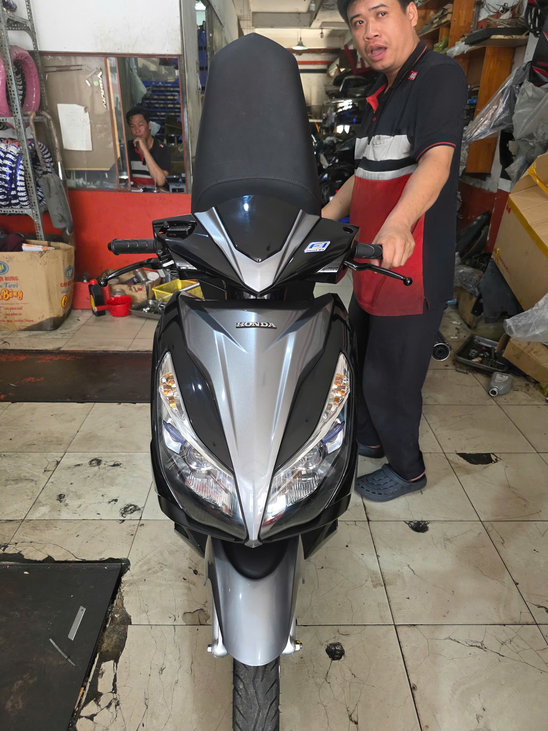 Mechanic presenting the fully restored Honda Air Blade after a complete scooter restoration service in the workshop.